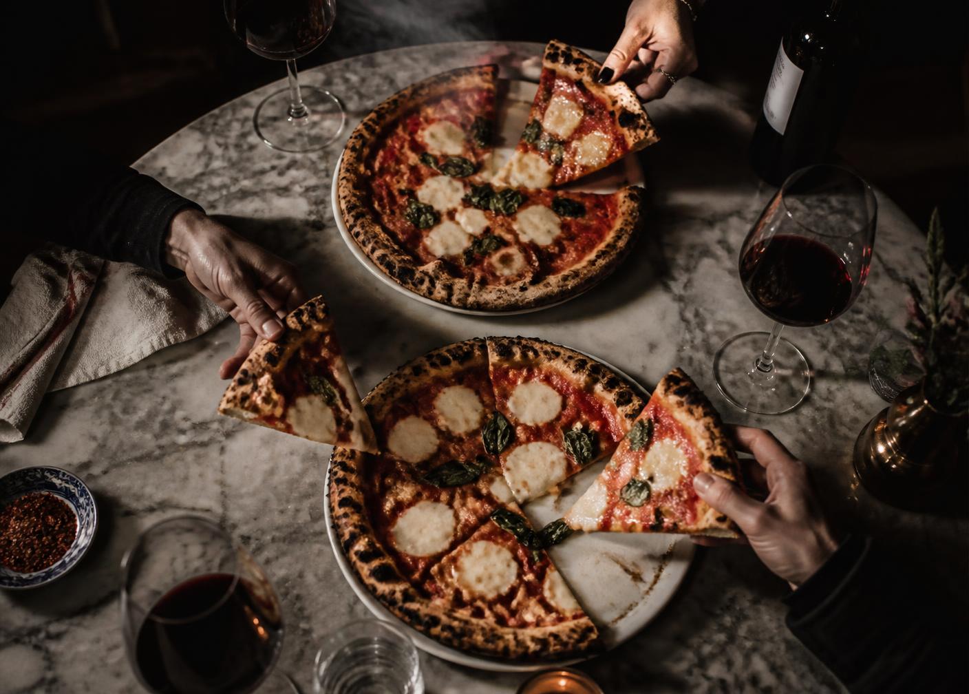 Overhead flat-lay of antipasti, wine and a lit candle on a set table